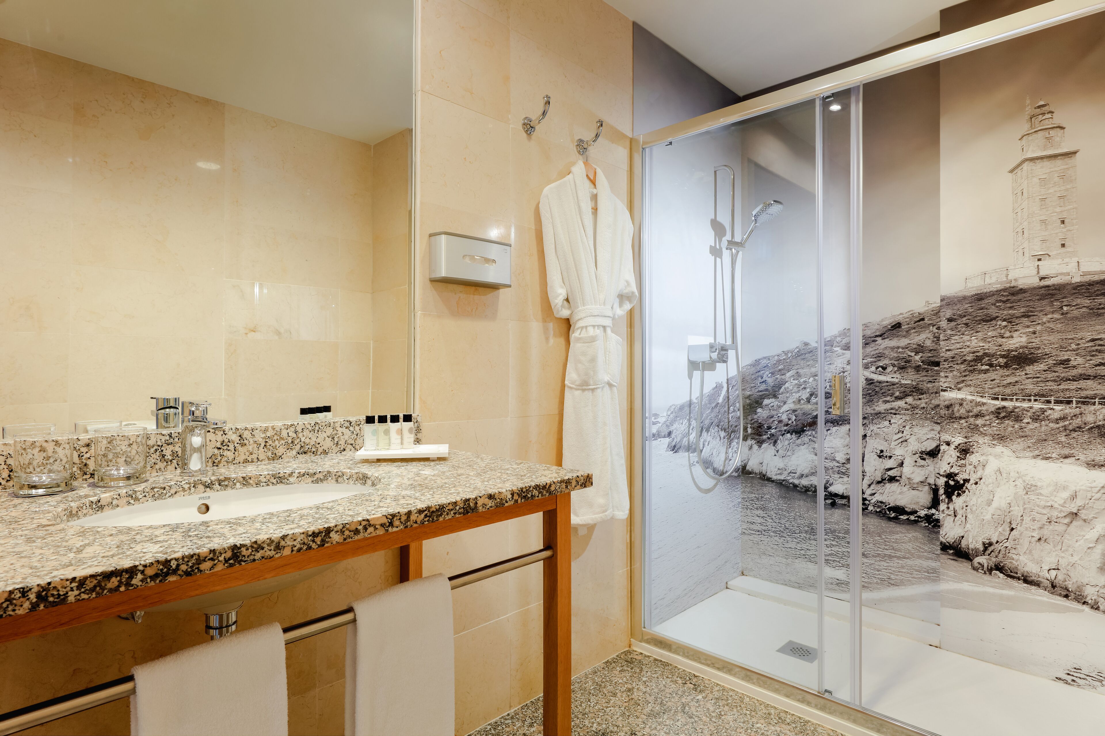 A bathroom with a granite countertop sink, a glass shower enclosure, and a towel rack.