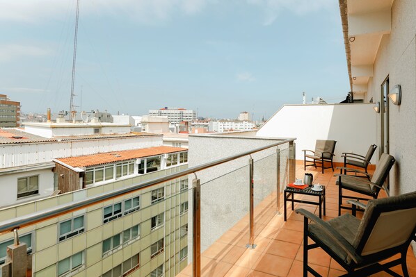 Un balcón con vistas a la ciudad, amueblado con sillas y una mesa.