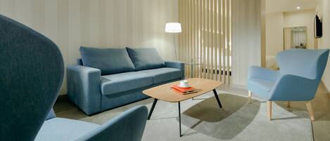 A modern living room with a blue sofa, a matching armchair, and a wooden coffee table.