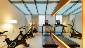A gym with exercise equipment, including a treadmill and stationary bikes, and a large window providing natural light. - Hesperia A Coruña Centro (A Coruña)