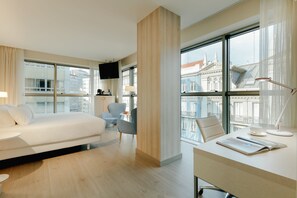 A modern hotel room with a bed, a desk with a cup and a book, a chair, and a TV. - Hesperia A Coruña Centro (A Coruña)