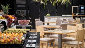 A restaurant with a buffet setup, including fruits and vegetables, and a seating area with tables and chairs. - Hesperia A Coruña Centro (A Coruña)