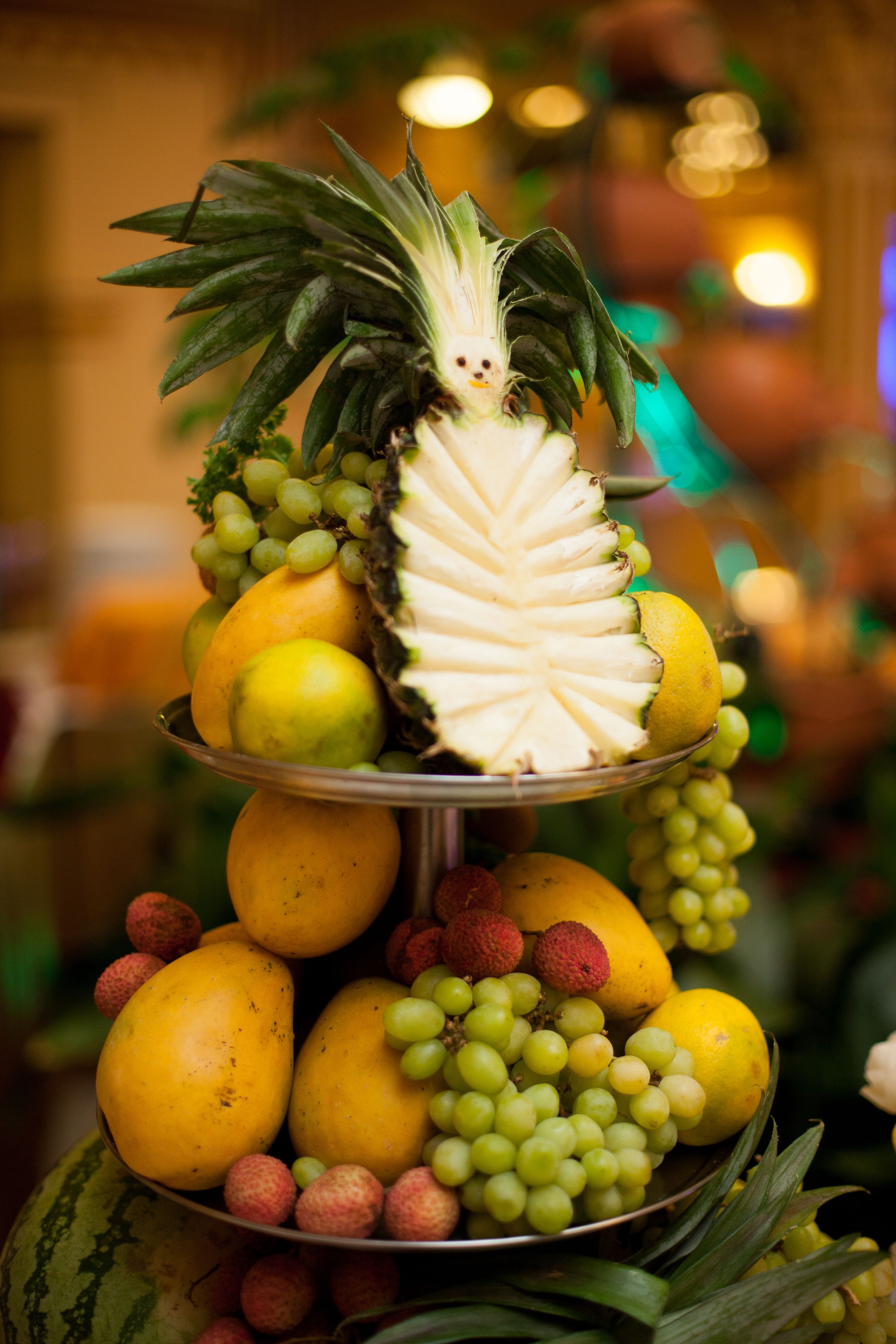 A multi-tiered fruit display with various fruits and a pineapple.