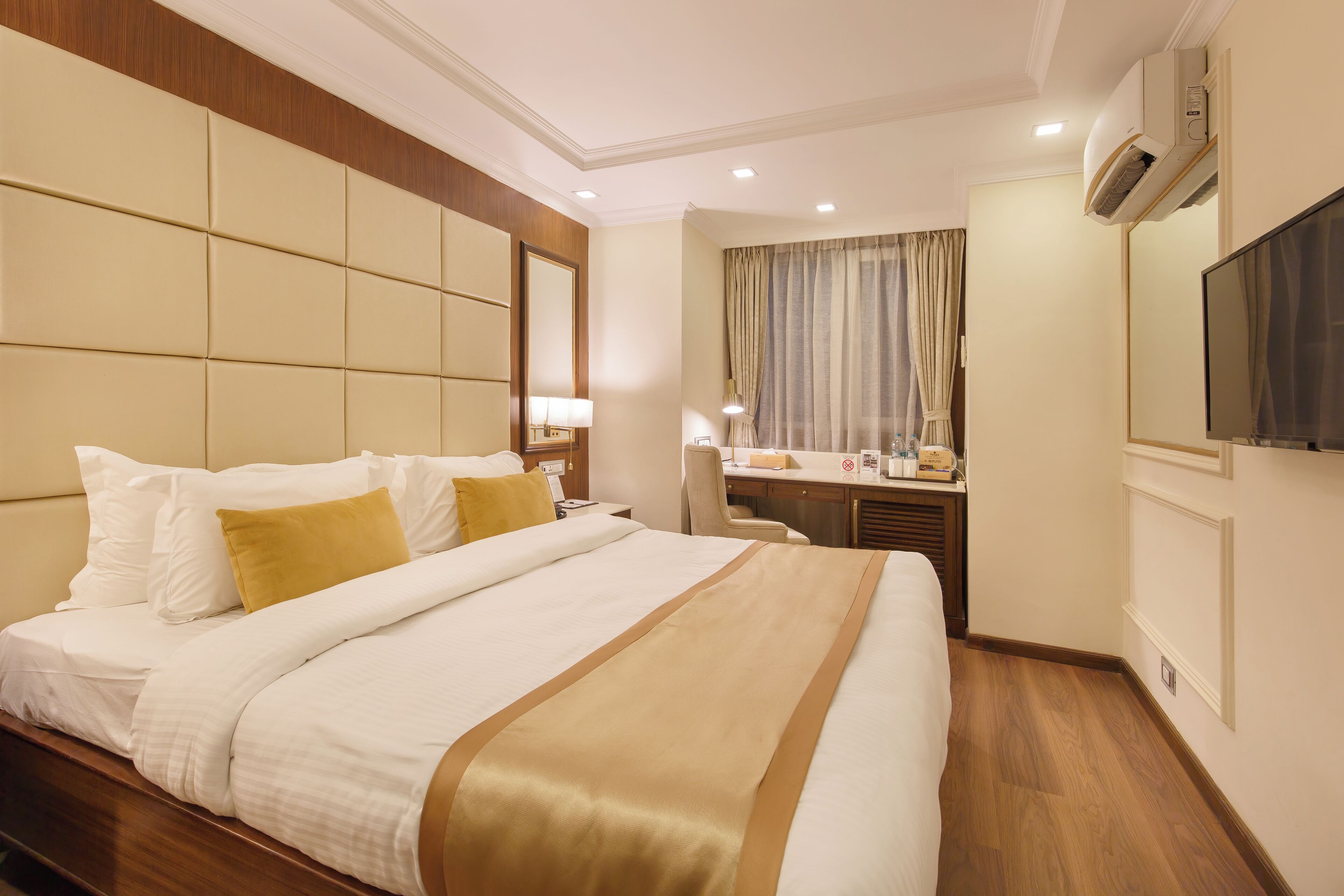 Una habitación de hotel con una cama grande, un escritorio, una silla y un televisor.