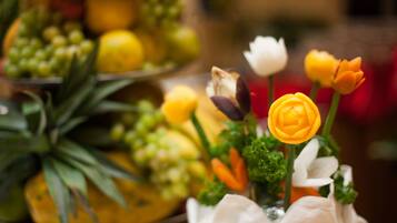 A table with a fruit arrangement and a vase with flowers.