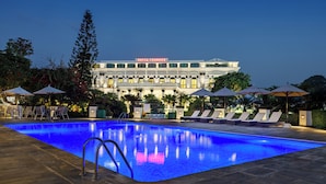 A hotel with a swimming pool, lounge chairs, and umbrellas. - Hotel Shanker-Palatial Heritage Kathmandu (Kathmandu)