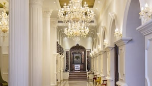 A grand hallway with a large chandelier, columns, and red chairs. - Hotel Shanker-Palatial Heritage Kathmandu (Kathmandu)