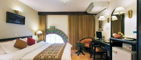 Habitación de hotel con cama, escritorio, silla, una mesita y aire acondicionado.
