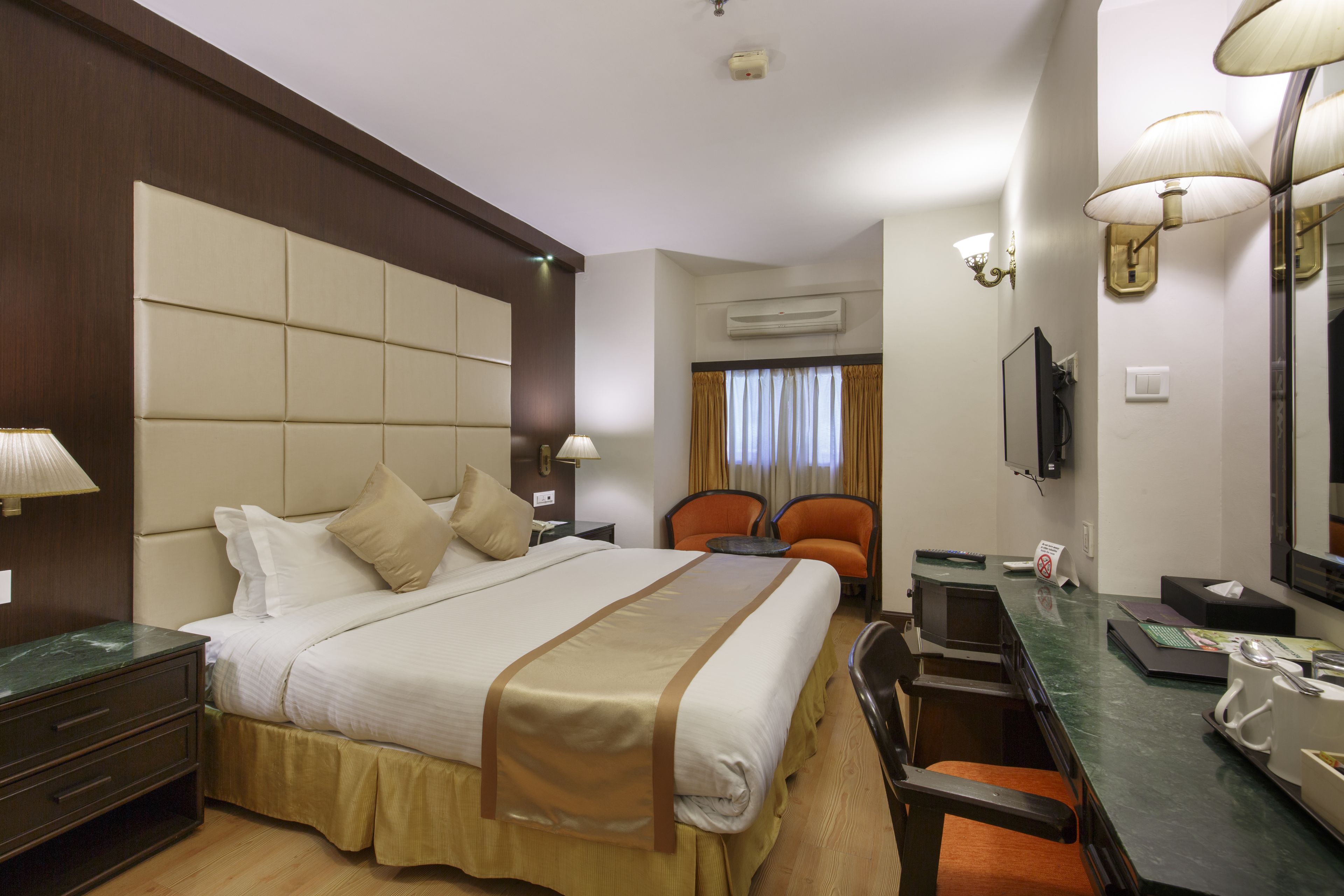 A hotel room with a large bed, a desk, a chair, and a television.
