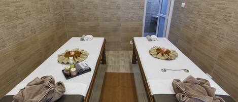 A spa room with two massage tables, towels, and a tray with amenities.