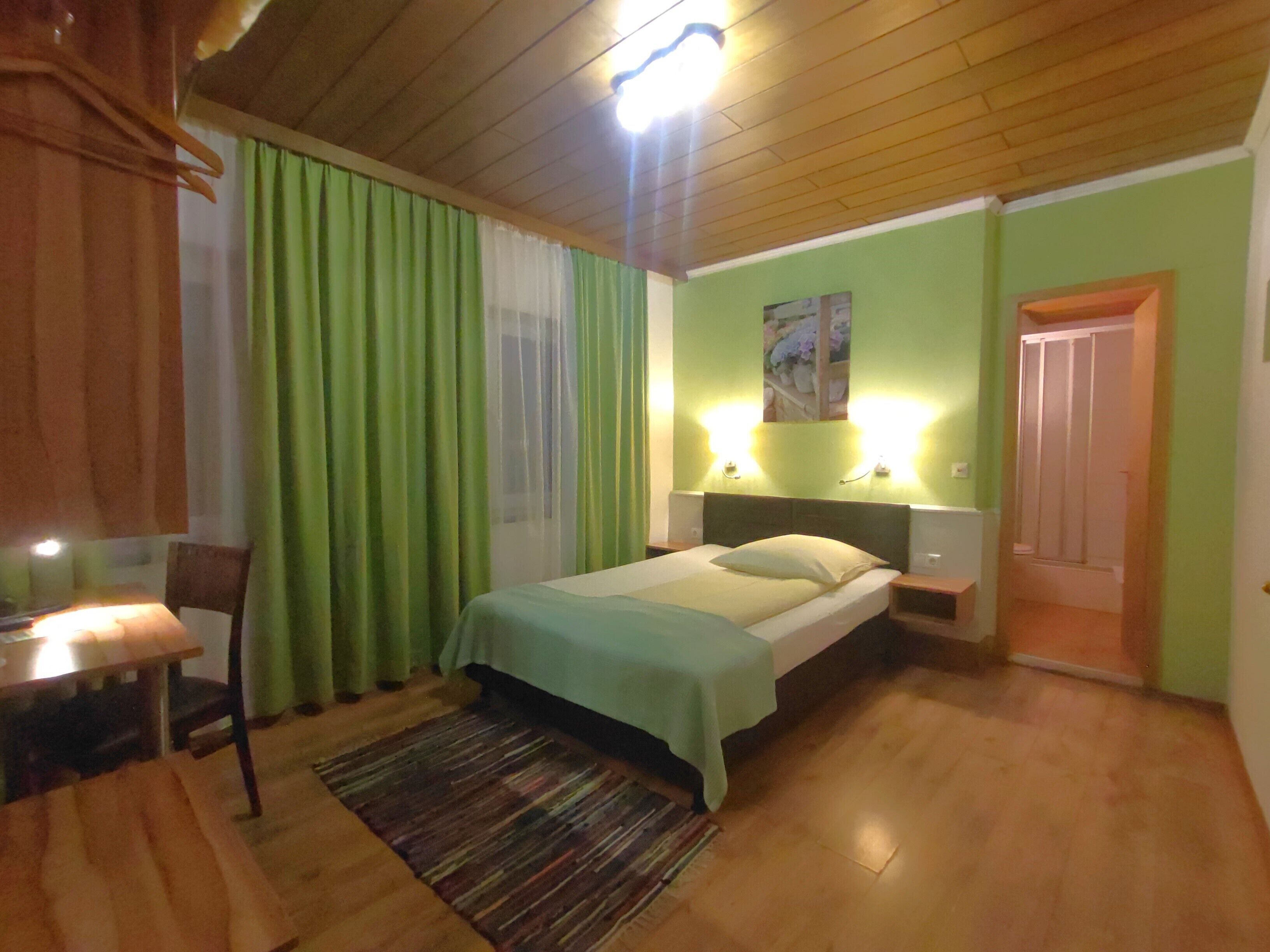 Un dormitorio con una cama, una mesita de noche, una silla, una mesa y una puerta.