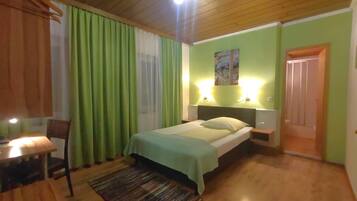 Un dormitorio con una cama, una mesita de noche, una silla, una mesa y una puerta.