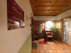 A hotel lobby with a breakfast sign, a reception desk, and a dining area with chairs and a table. - Hotel Smart-Inn (Erlangen)