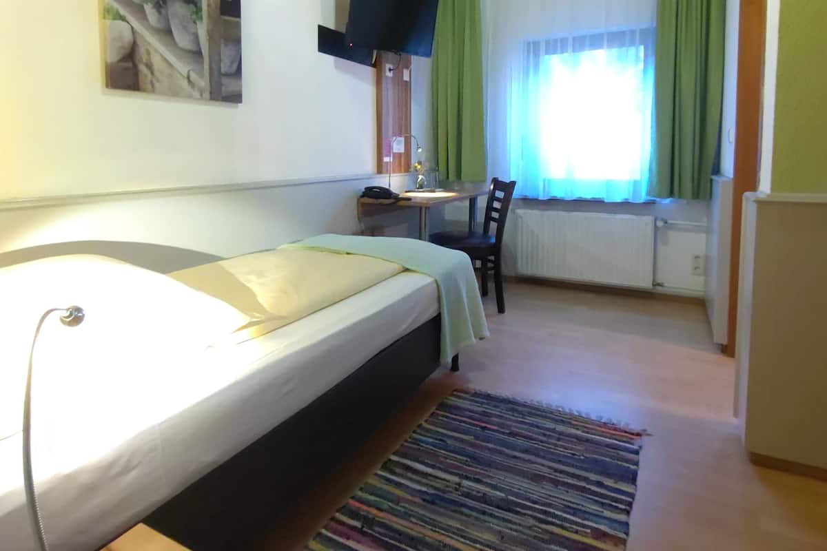 A small, cozy room with a bed, a desk, and a television.