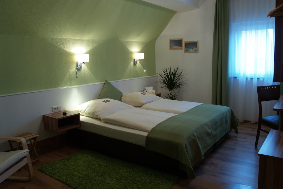 A bedroom with a bed, bedside tables, a desk, and a chair.