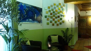 Un salon avec un grand tableau abstrait, un mur vert et blanc, un canapé, une table basse et un lampadaire.