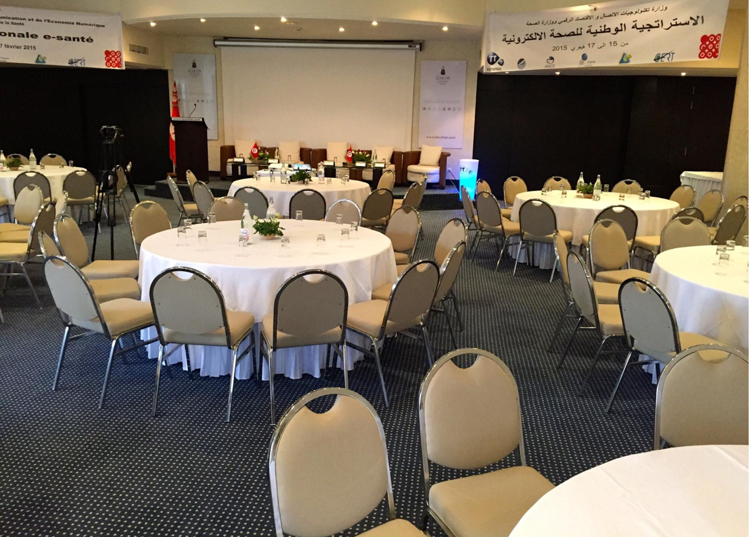 A conference room with round tables and chairs, equipped with nameplates and water bottles.