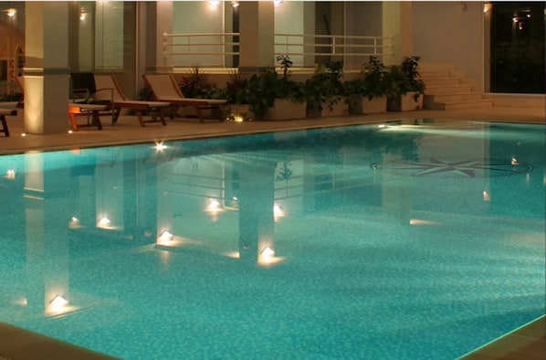 Una piscina cubierta, una piscina al aire libre, tumbonas