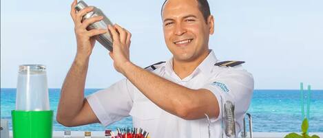 A bartender preparing a drink with a view of the ocean in the background.