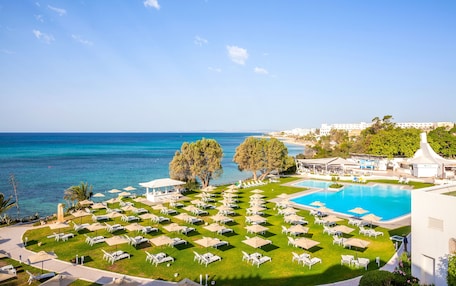 A resort with a pool, sun loungers, and a view of the sea.