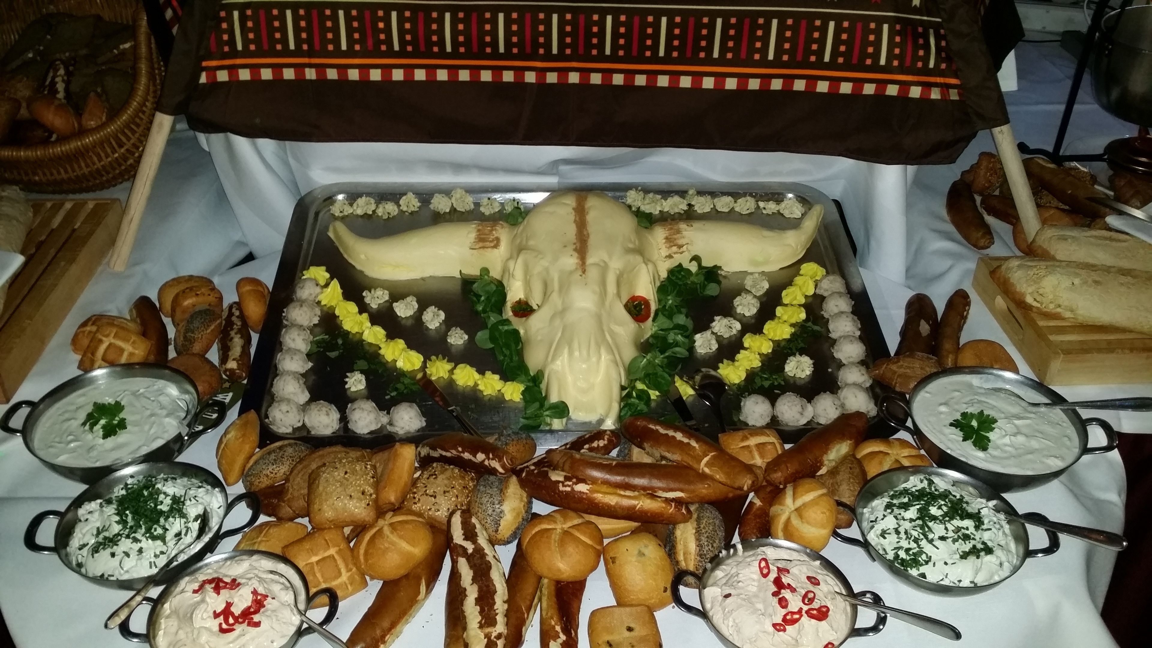 A buffet table with various breads, rolls, and dips.