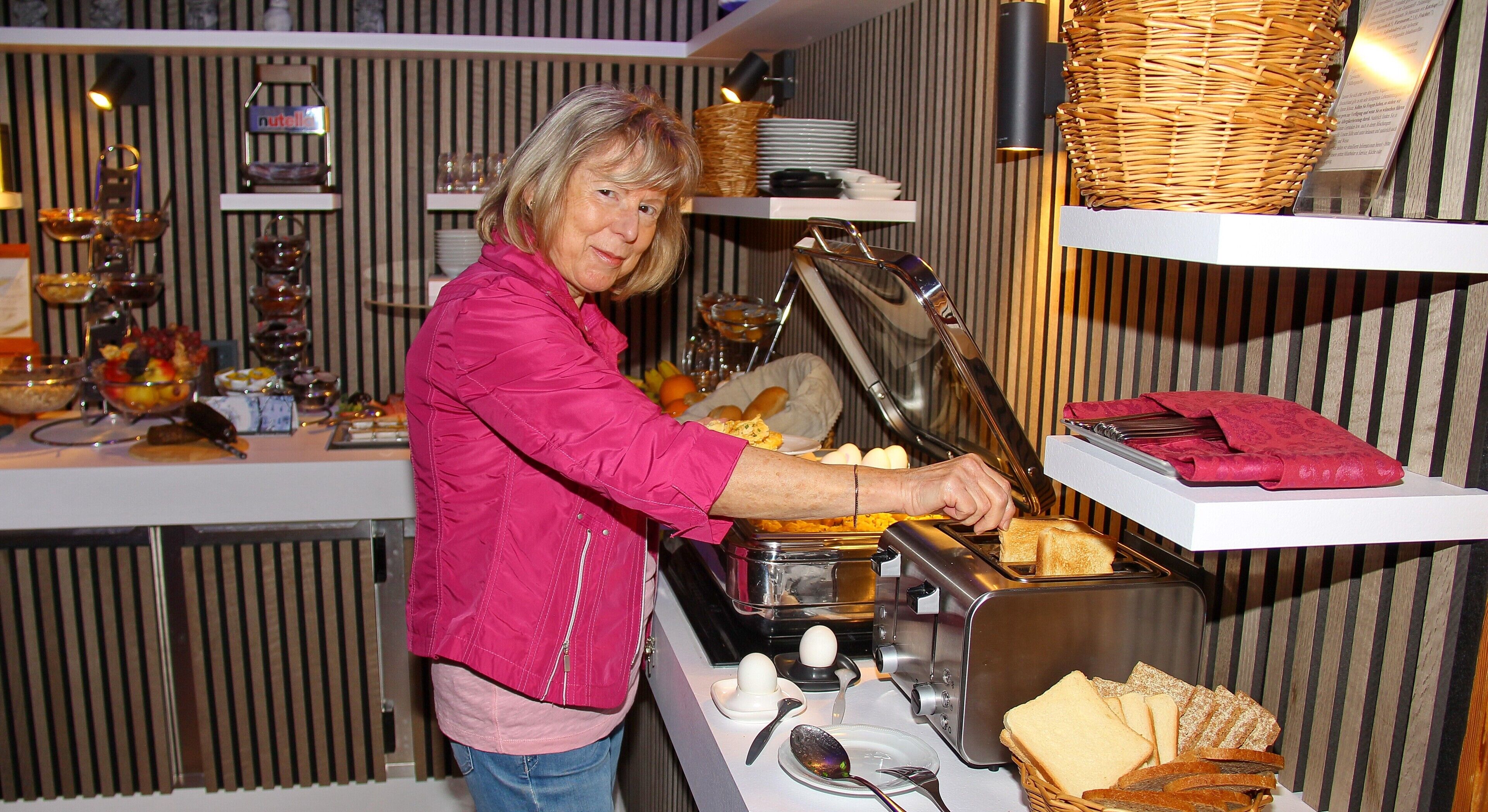 A buffet setup with various food items and a person serving food.