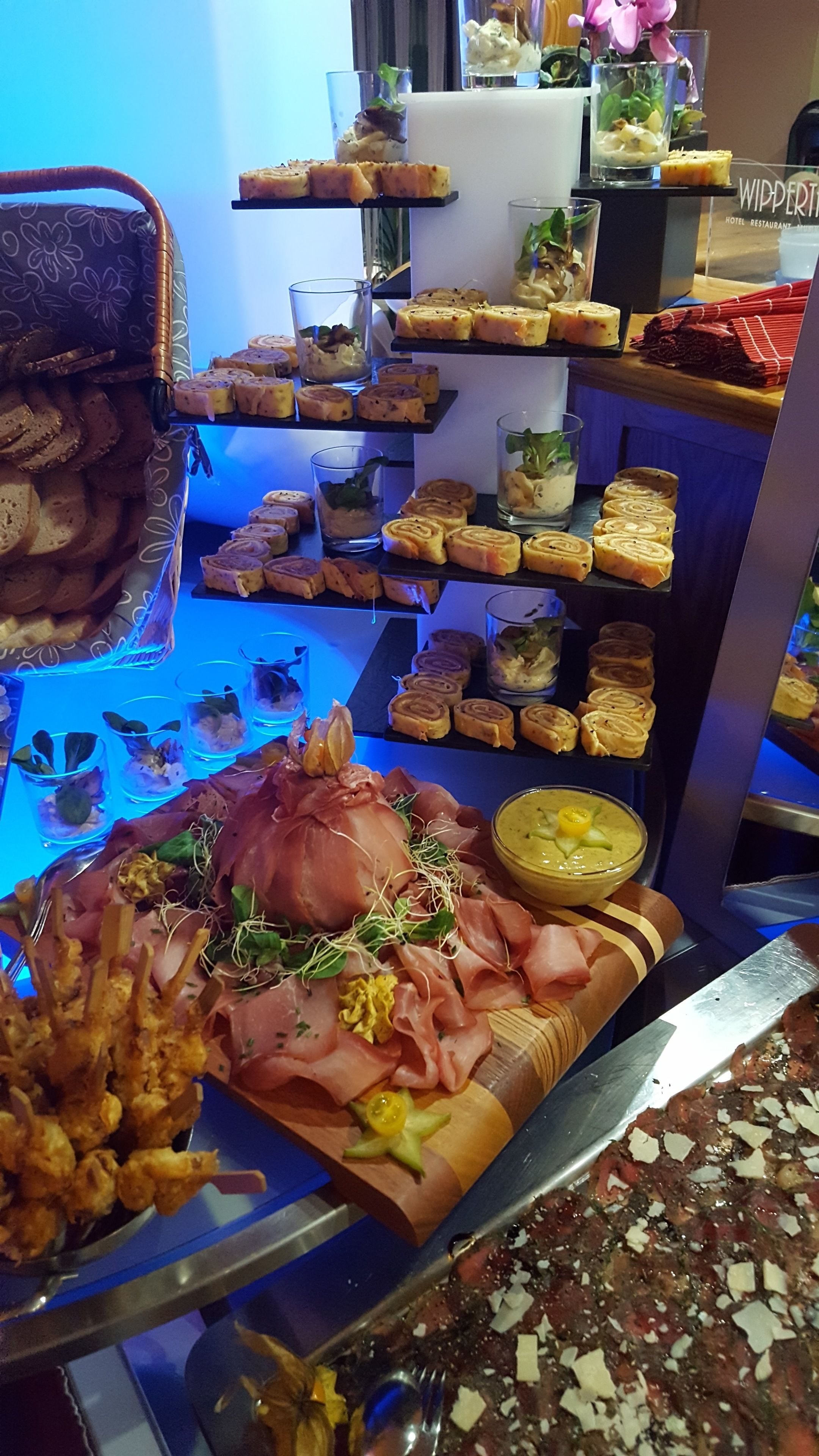Un bufé con diversos alimentos, incluyendo carnes, quesos y postres.