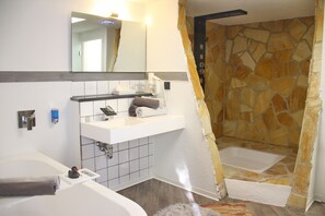 A bathroom with a bathtub, a shower, a sink with a mirror, and a towel rack. - Hotel Wippertal (Ilberstedt)