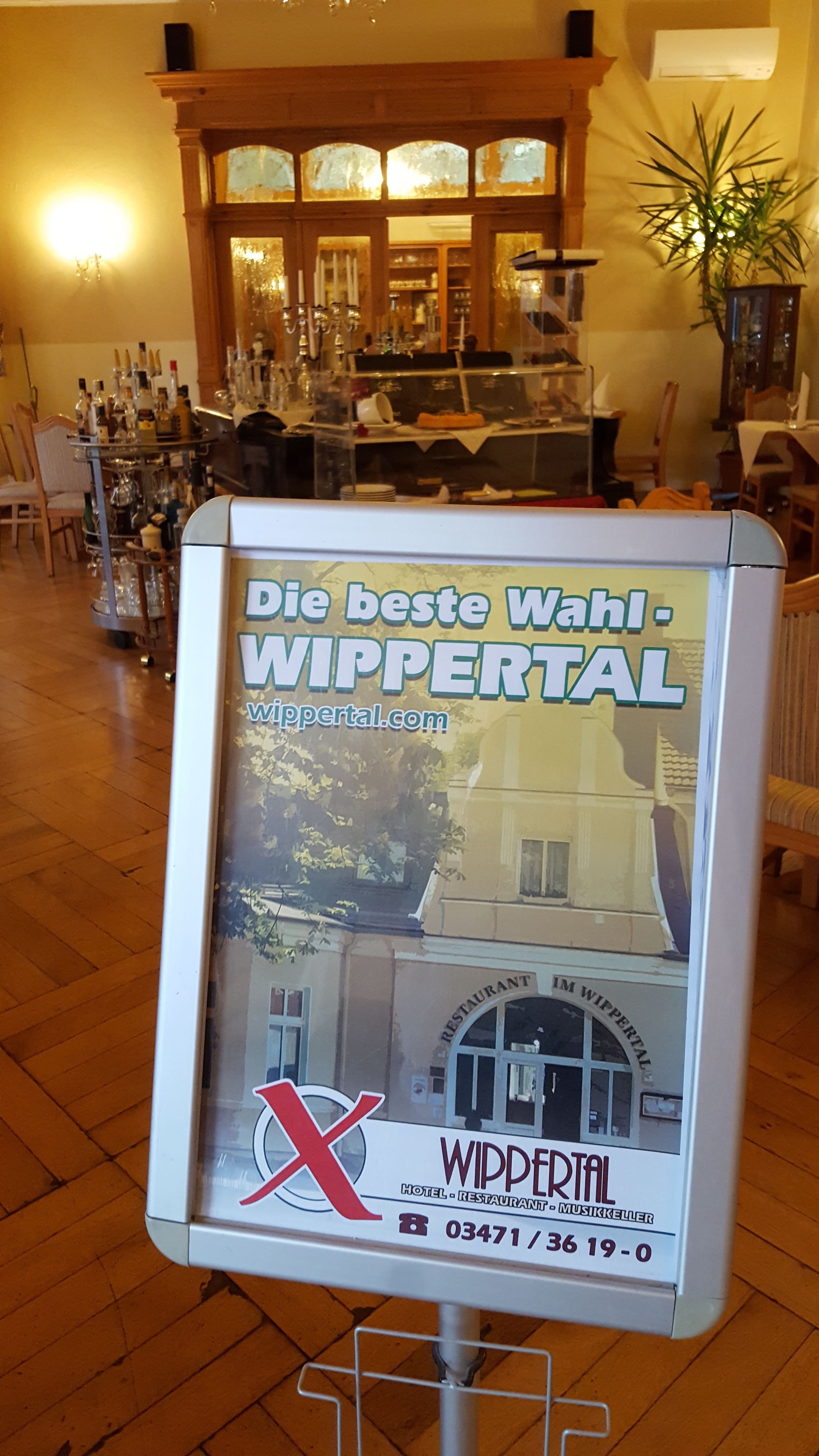 A sign for Wippertal hotel and restaurant with a view of the interior including a bar and dining area.