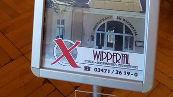 A sign for Wippertal hotel and restaurant with a view of the interior including a bar and dining area.