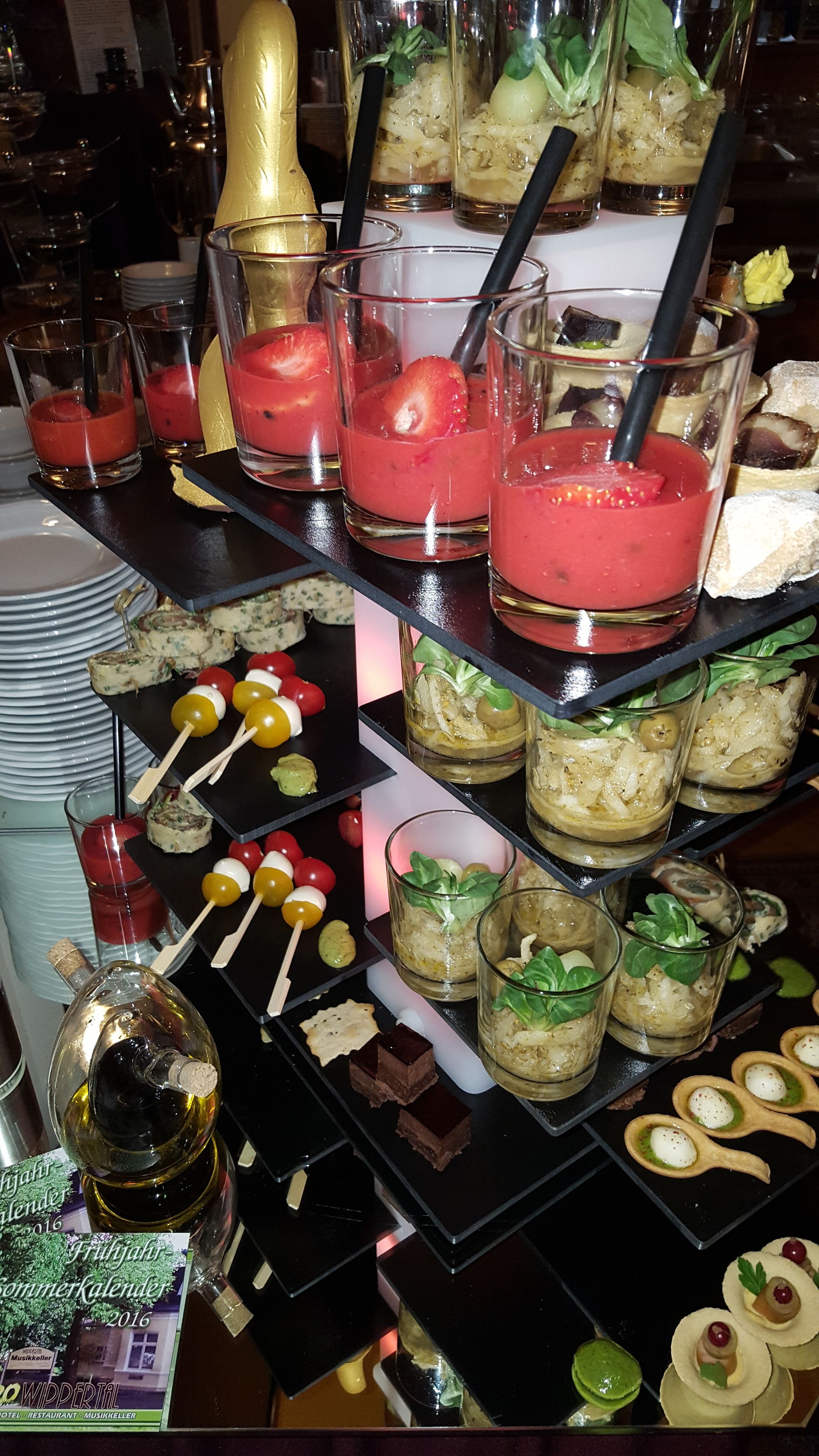A multi-tiered dessert display with various types of desserts and drinks.