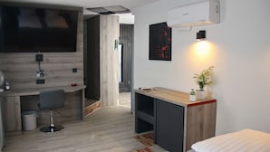 A modern hotel room with a flat-screen TV, a desk with a chair, a bed, and a small potted plant. - Hotel Wippertal (Ilberstedt)