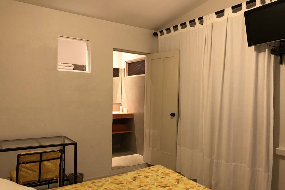 Ein Schlafzimmer mit Bett, Schreibtisch, Stuhl, Kleiderschrank und Fernseher.