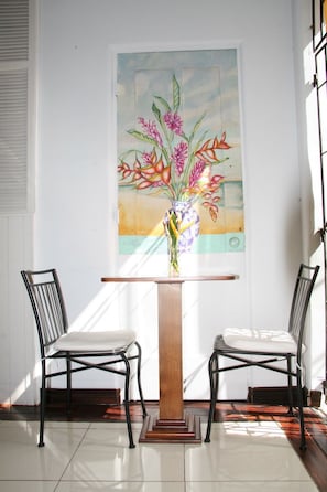 Une pièce avec un mur blanc, une table en bois avec deux chaises et un tableau représentant des fleurs.