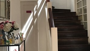 Una escalera con escalones de madera oscura y barandillas blancas, que lleva a una puerta con un letrero rojo.