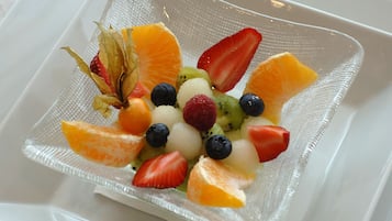 Una fuente de vidrio cuadrada con una ensalada de frutas sobre una bandeja blanca.