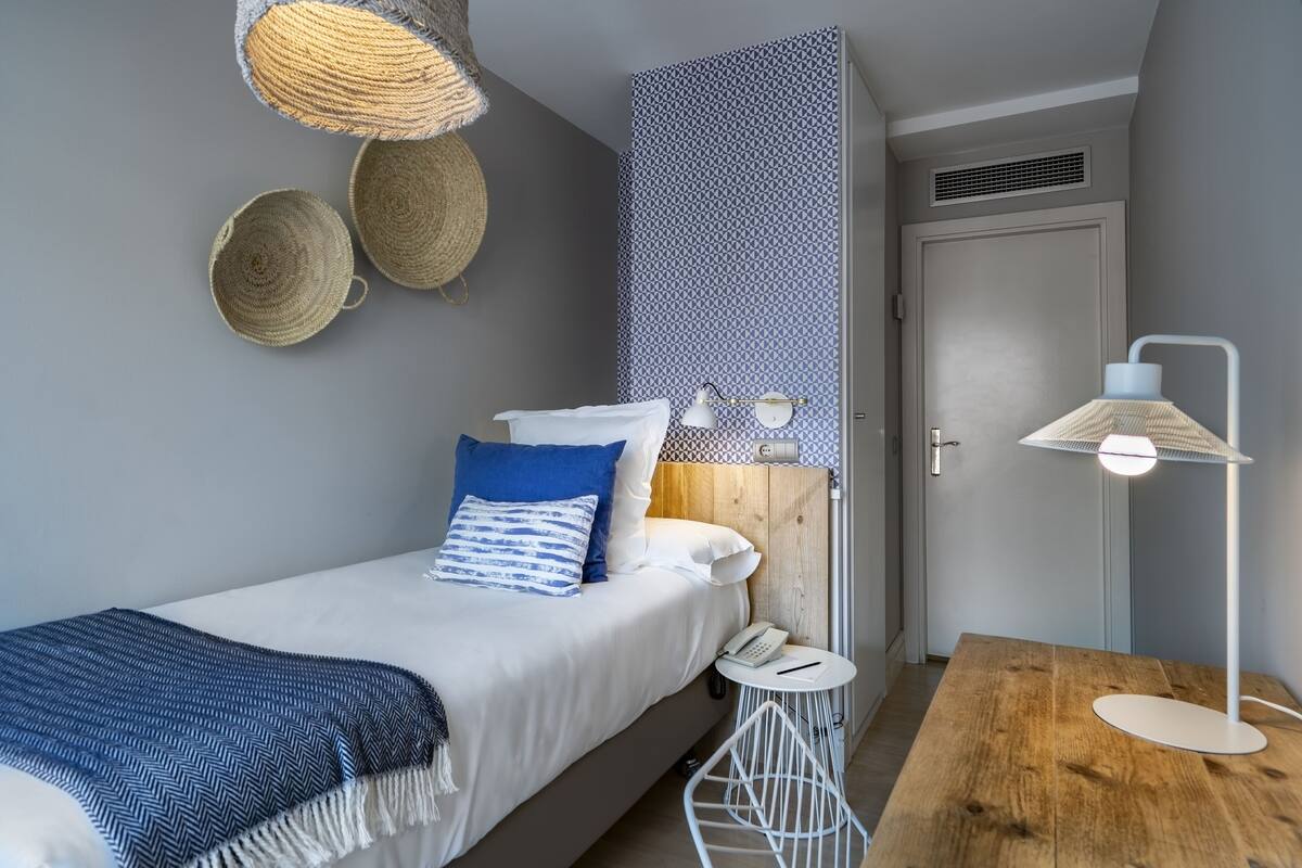 A neatly arranged bedroom with a bed, bedside table, lamp, and wall decor.