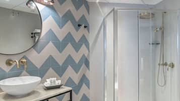 Un baño moderno con un lavabo blanco grande, un espejo y una ducha con puerta de cristal.