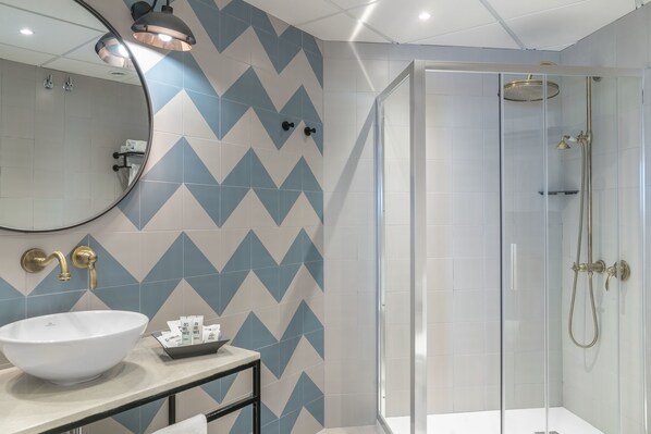 A modern bathroom with a large white sink, a mirror, and a shower with a glass door.