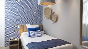 Une chambre à coucher comprenant un lit, une table de chevet, une lampe et un luminaire fixé au mur.