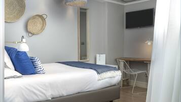 Un dormitori modern amb llit, taulella, làmpada, decoració mural teixida i televisió.