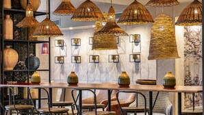 A bar area with wicker pendant lights, black metal chairs, and decorative vases on the counter. - Hotel Vincci Puertochico (Santander)