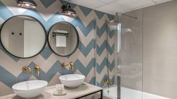 Un baño moderno con dos lavamanos, un espejo grande y una ducha.