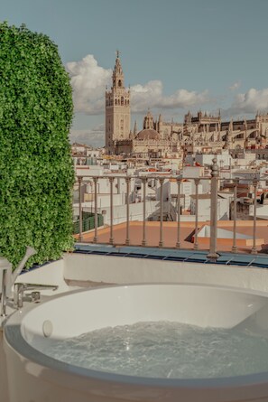 Terrat amb banyera hidromassatge i vista d'un edifici històric.