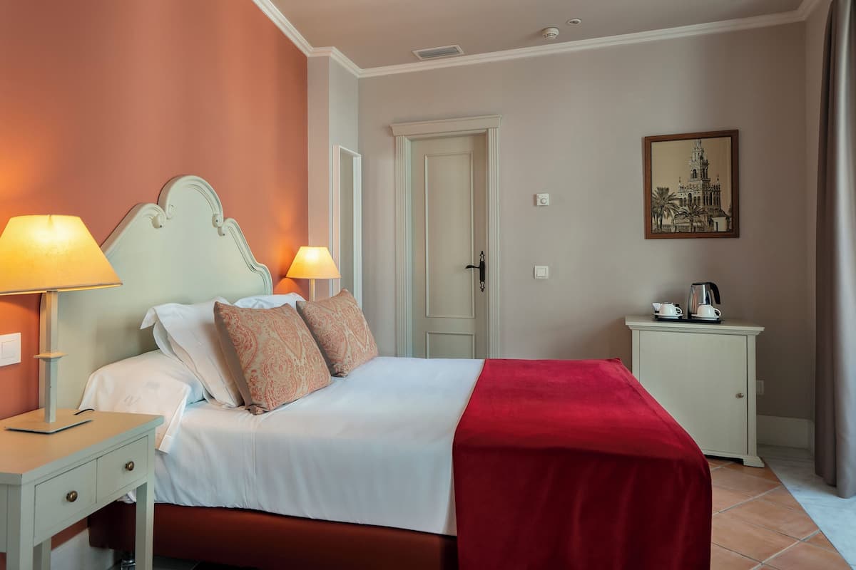 A neatly arranged bedroom with a bed, bedside tables, a nightstand, a door, and a small cabinet.