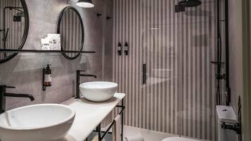 Un baño moderno con un espejo redondo grande, un lavabo blanco y una zona de ducha.
