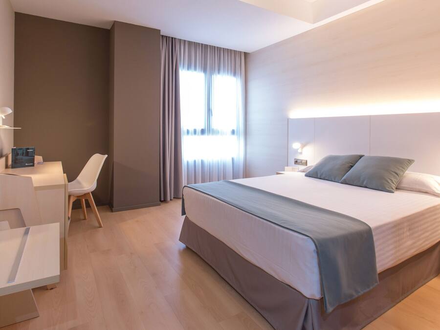 Een moderne hotelkamer met een groot bed, een bureau, een stoel en een televisie.