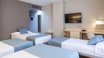 Una habitación de hotel con dos camas individuales, un escritorio, una silla, un televisor y un minibar.