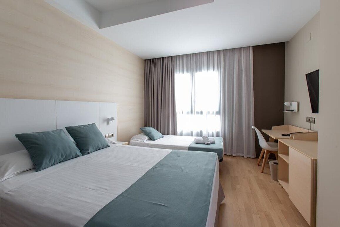 Une chambre d’hôtel avec deux lits, un bureau, une chaise et un téléviseur.
