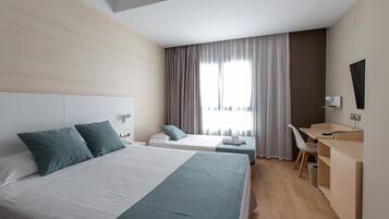 Une chambre d’hôtel avec deux lits, un bureau, une chaise et un téléviseur.